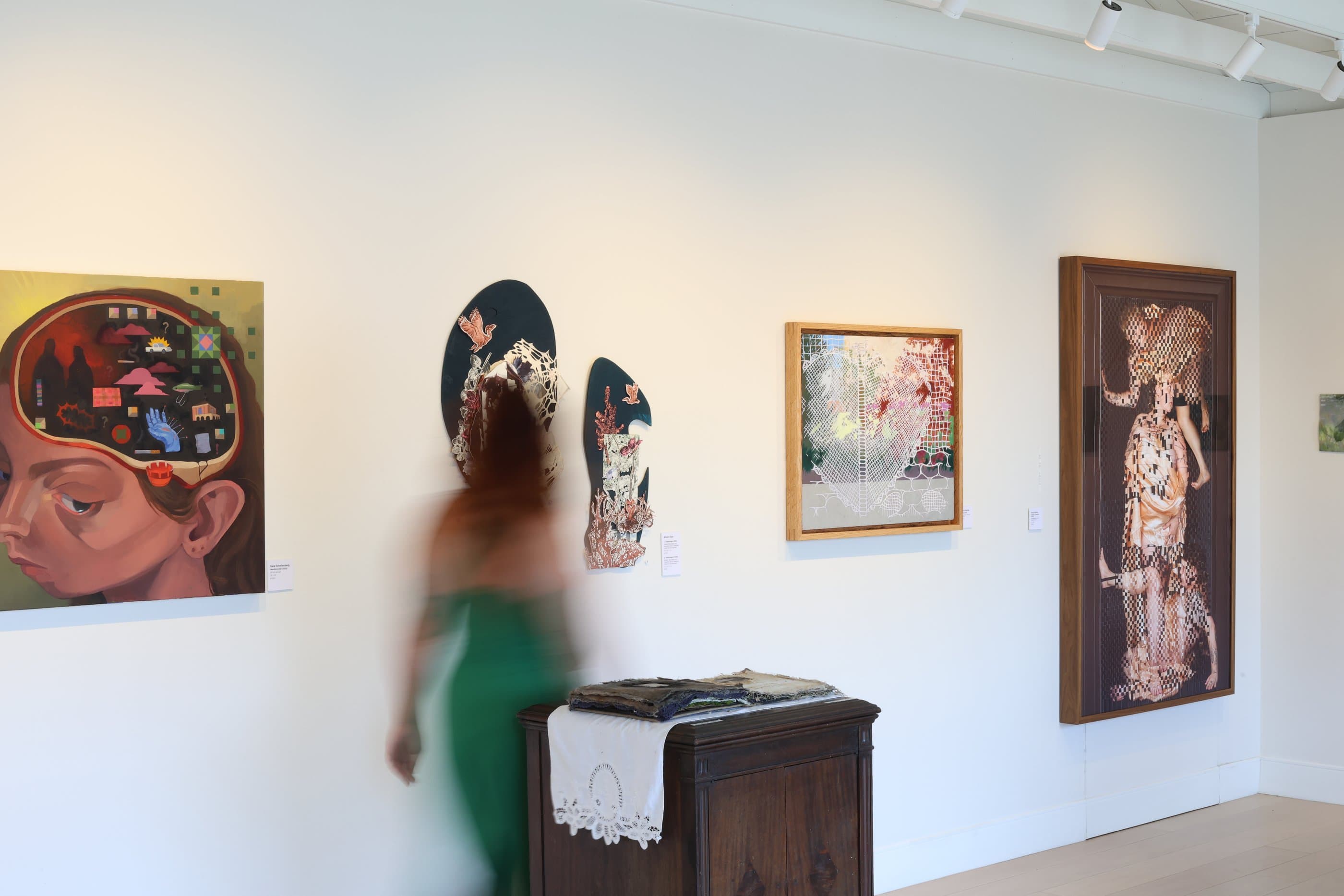 A visitor viewing paintings inside Midnight Gallery